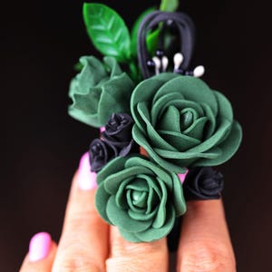 a woman's hand holding a ring with flowers on it