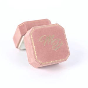 A pink velvet box with the initials "MD" embossed on it.