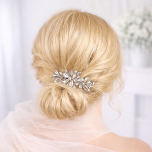 a close-up view of a woman's blonde hair with a decorative hair accessory, possibly a hair clip or brooch, on the back of her head.