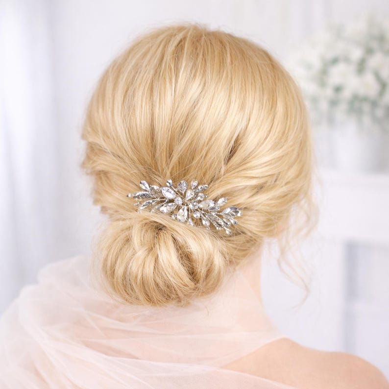 a close-up view of a woman's blonde hair with a decorative hair accessory, possibly a hair clip or brooch, on the back of her head.