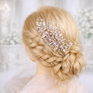 A close-up of a woman's blonde hair with a decorative hair accessory, possibly a flower or crystal piece, in the back of her head.