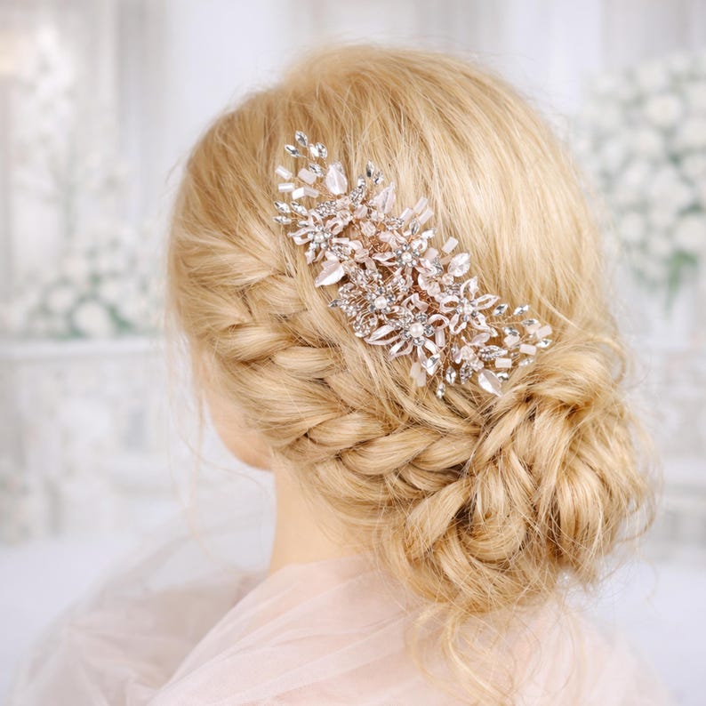 A close-up of a woman's blonde hair with a decorative hair accessory, possibly a flower or crystal piece, in the back of her head.