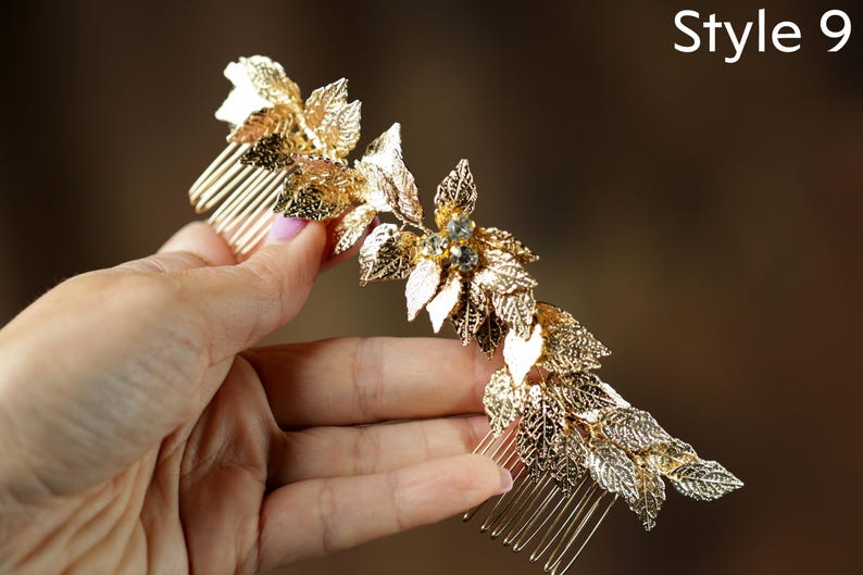 A hand holding a decorative gold hair accessory with leaves and gemstones.