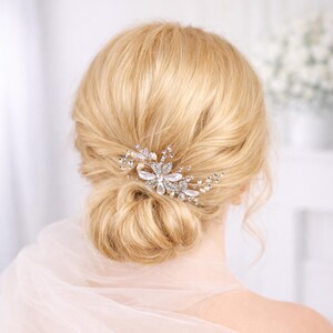 A close-up view of a woman's blonde hair with a decorative hair accessory, possibly a flower or crystal piece, in the back of her head.