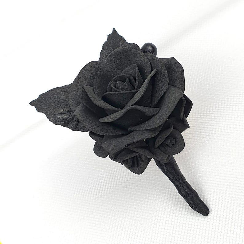 a single black rose on a white cloth