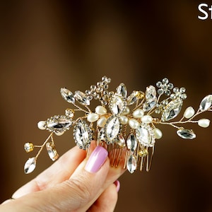 A hand holding a decorative hair accessory with a floral design and sparkling gemstones.