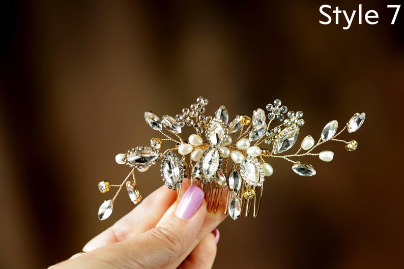 A hand holding a decorative hair accessory with a floral design and sparkling gemstones.