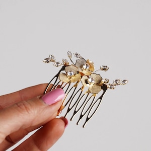 A hand holding a decorative hair accessory with a floral design.