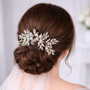 a woman's back view with her hair styled in a bun, adorned with a decorative hair accessory featuring small, sparkling stones.