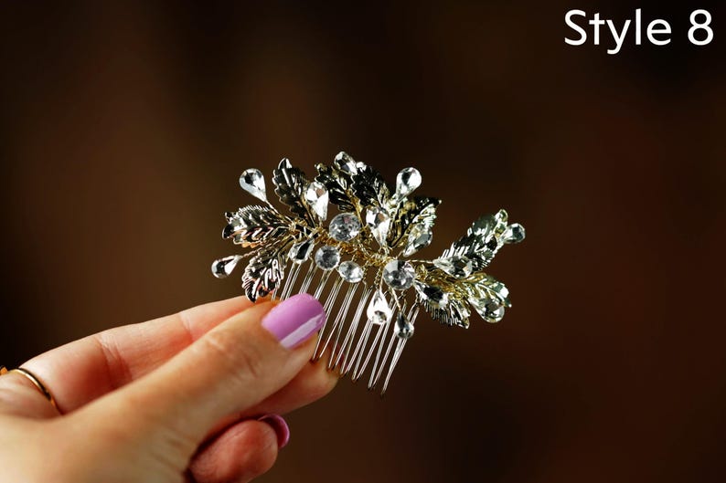 A hand holding a decorative hair accessory with a floral design and sparkling crystal elements.