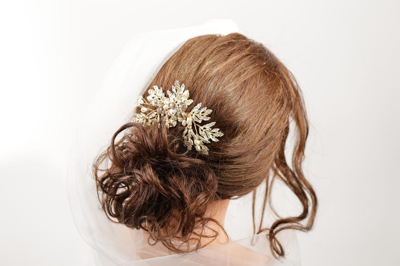 A close-up view of a woman's hair, with a decorative hair accessory, possibly a veil or headpiece, visible.