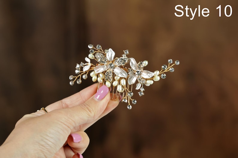 A hand holding a decorative hair accessory with flowers and pearls.