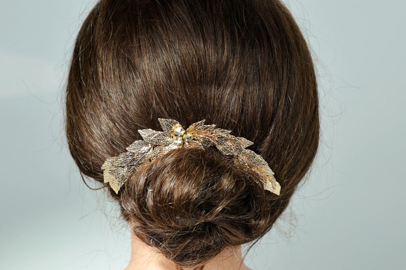 the back of a person's head with a decorative hair accessory, featuring a combination of leaves and flowers.