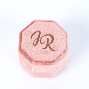 A pink velvet box with the initials "JR" printed on it.