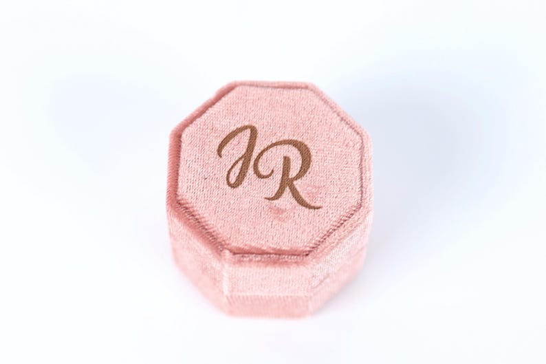 A pink velvet box with the initials "JR" printed on it.