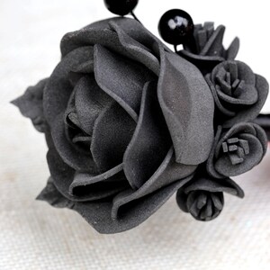 a woman's hand is holding a black flower