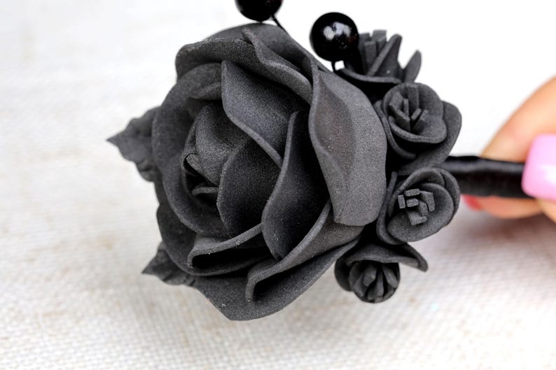 a woman's hand is holding a black flower