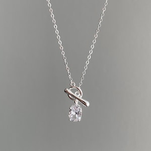 Puede incluir: Un collar de plata con cierre de palanca y un solo colgante de cristal transparente.