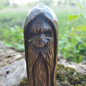 A 3.6-inch tall hand-carved linden wood figurine of a forest spirit. The figure has a long, flowing beard with deep textures and a face partially hidden under a hood. The dark brown stain highlights the artisan's hand-cut marks. This unique piece of Ukrainian folk art has a matte beeswax finish and a rustic, mystical appearance, shown against a neutral background.