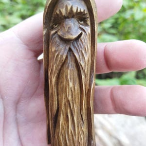 A 3.6-inch tall hand-carved linden wood figurine of a forest spirit. The figure has a long, flowing beard with deep textures and a face partially hidden under a hood. The dark brown stain highlights the artisan's hand-cut marks. This unique piece of Ukrainian folk art has a matte beeswax finish and a rustic, mystical appearance, shown against a neutral background.