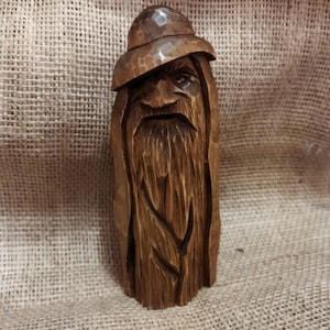Odin wood spirit statue carved by hand. Wooden Odin figurine with a wise, stern gaze, carved from a single branch of forest tree