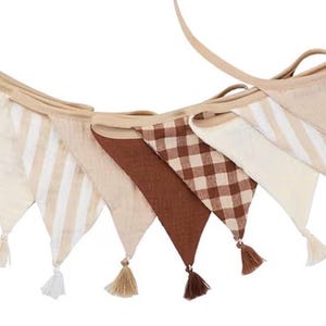 May include: A fabric bunting banner featuring a series of triangular pennants in alternating patterns and solid colors. The design includes brown gingham checks, solid brown, cream, and cream-and-white stripes, each finished with a small tassel.