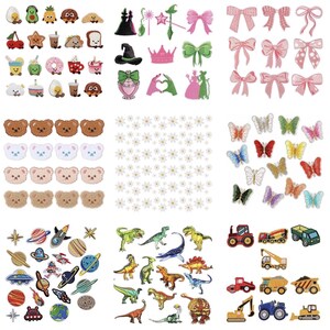 May include: A collection of embroidered iron-on patches featuring various designs including food items, bows, teddy bear faces, daisies, butterflies, space elements, dinosaurs, and construction vehicles arranged in a grid of nine distinct sections.