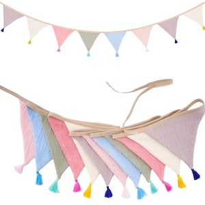 May include: A fabric bunting banner featuring a series of triangular flags in pastel shades of pink, blue, green, cream, and lavender. Each triangular flag is finished with a small, matching colored tassel attached to the bottom point.