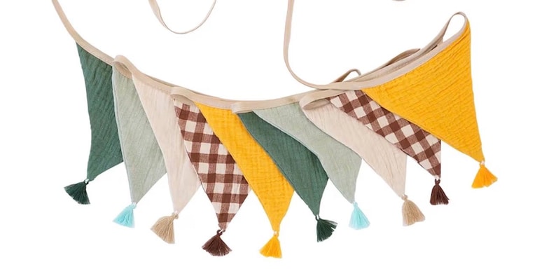 May include: A fabric bunting banner featuring triangular flags in solid mustard yellow, sage green, and cream, alternating with brown and white gingham checkered flags. Each flag is finished with a small matching tassel at the bottom point.