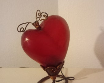 Lámpara vintage en forma de corazón con base de metal y la forma de corazón está hecha de algún tipo de resina.