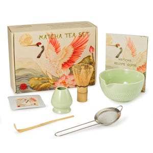 May include: Matcha tea set with a box featuring a crane illustration. The set includes a whisk, bowl, sifter, scoop, and a recipe guide. The bowl and small container are light green. The box reads "Matcha Tea Set".