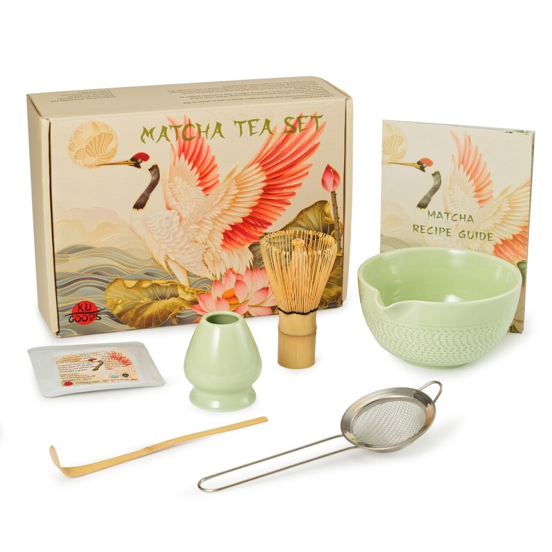 May include: Matcha tea set with a box featuring a crane illustration. The set includes a whisk, bowl, sifter, scoop, and a recipe guide. The bowl and small container are light green. The box reads "Matcha Tea Set".