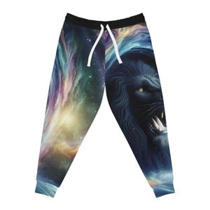 Könnte beinhalten: Jogginghose mit einem lebendigen kosmischen Design. Die Hose zeigt einen schwarzen Löwenkopf mit offenem Maul, vor dem Hintergrund wirbelnder Nebel in Blau-, Lila- und Gelbtönen. Der Bund ist schwarz mit einem weißen Kordelzug.