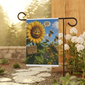 Könnte beinhalten: Eine Gartenflagge mit einer lächelnden Sonnenblume und Bienen, die Nektarbeutel tragen. Die Flagge trägt die Aufschriften "Come Visit!" und "Bee Our Guest! Take Nectar Home With You!" vor blauem Himmel.