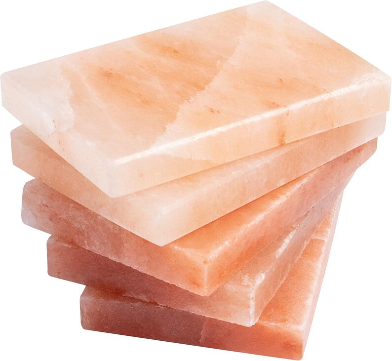 May include: A stack of five rectangular pink Himalayan salt slabs. The slabs are smooth and have a natural, slightly rough texture.