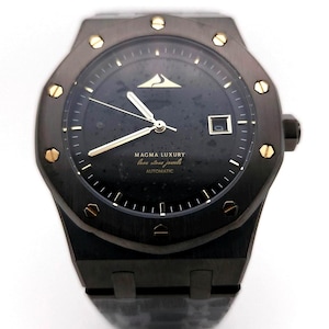 May include: A dark gray luxury wristwatch with a black face and gold accents. The watch features a date window and the text "MAGMA LUXURY" and "Automatic". The watch has a dark gray band and gold-colored screws around the bezel.