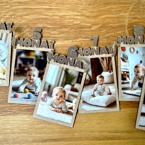 Guirnaldas de fotos de madera con tarjetas de hitos que representan el primer año de vida de un niño, como decoración para el cumpleaños del primer año.