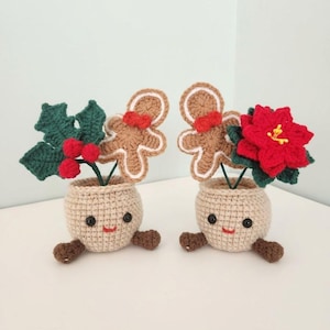 May include: Two beige crocheted pots with smiling faces, black bead eyes, and small brown feet. One pot holds a green holly sprig with red berries and a gingerbread man. The other holds a red poinsettia and a gingerbread man.