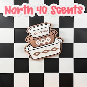 May include: A stack of three decorative casserole dish stickers with a brown and white design. The top sticker has a simple design, the middle sticker has a floral design, and the bottom sticker has a diamond design. The text "North 40 Scents" is above the stickers.