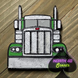 May include: A green and silver 3D printed model of a semi-truck. The truck has a large grill and headlights. The model is on a wooden surface. The text "NORTH 40 Scents" is visible in the lower right corner of the image.