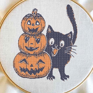 以下が含まれることがあります： 大きく笑った黒い猫が、彫刻された顔をしたオレンジ色のカボチャ3つの積み重ねの横に立っています。カボチャは一番小さいものが上にくるように積み重ねられています。