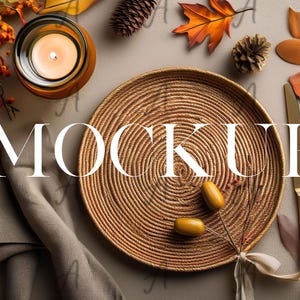 Könnte beinhalten: Ein runder geflochtener Platzteller in natürlicher brauner Farbe mit einem Spiralmuster. Der Platzteller liegt auf einer hellgrauen Oberfläche mit Herbstdekorationen, darunter eine Kerze, Blätter und Eicheln.