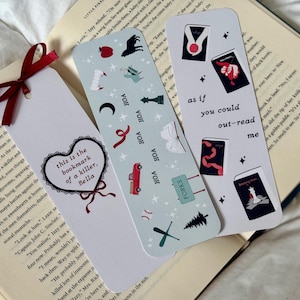 Pode incluir: Três marcadores de livros decorativos. Um apresenta um coração com o texto "this is the bookmark of a killer, Bella". Outro tem o texto "as if you could out-read me". O terceiro marcador de livros tem várias ilustrações pequenas.