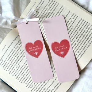 May include: Two pink bookmarks with a red heart design and the text "be mine, ballentine".