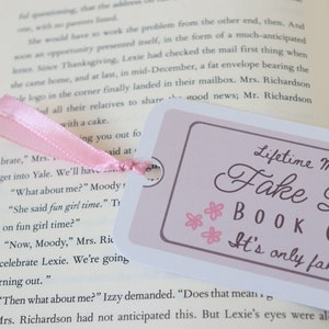 May include: A pink ribbon bookmark with the text "Lifetime Membership Fake Dating Book Club It's only fake, right?" printed on a white background with pink flowers.