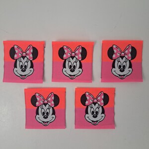 May include: Five pink and orange fabric patches with a cartoon image of Minnie Mouse. Each patch features Minnie Mouse with a pink bow and white polka dots.