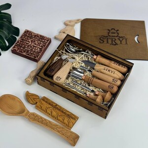 May include: A wooden box set containing carving tools and utensils, including a spoon, fork, and knife. The set includes a wooden stamp and a decorative wooden bunny. The box is branded with the word "STRYI".