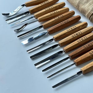 May include: A set of 10 wood carving tools with metal blades. The tools have wooden handles with the word "STRYI" engraved on them. The tools are arranged in a row on a white surface.