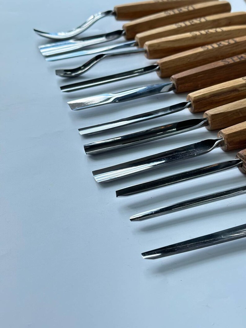 May include: A set of 12 wood carving tools with wooden handles. The tools have different shaped blades for carving wood.