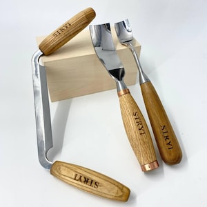 Puede incluir: Tres herramientas de talla con mango de madera y cuchillas de metal. Las herramientas están etiquetadas con "SIRYI" en los mangos. Las herramientas están sobre una superficie de madera clara.